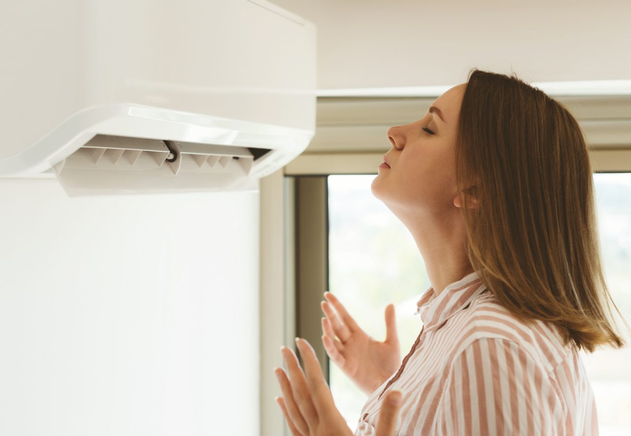 Women dying from the heat standing in front of the air conditioner.; Shutterstock ID 718824886; Purchase Order: -